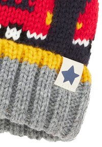 Bonnet tricoté avec un design rouge et marine, un revers côtelé gris, un accent jaune et une étiquette avec une étoile bleue. Texture en laine douce.