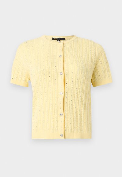 Κίτρινη πλεκτή ζακέτα με κοντά μανίκια, στρογγυλή λαιμόκοψη, κάθετο διάτρητο σχέδιο και έξι λαμπερά ασημένια κουμπιά στο μπροστινό μέρος.