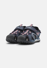 Sandalias azul marino con un diseño abierto, que cuentan con partes superiores de malla, correas ajustables y una suela de goma con agarre texturizado. Detalles en rojo y gris.