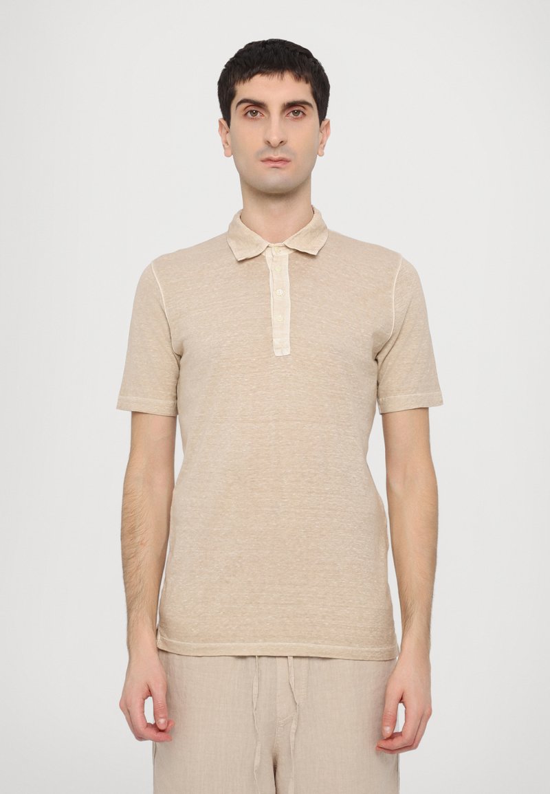 Camisa polo de manga corta color beige hecha de una tela texturizada, con un cuello suave y tres botones, que presenta un corte ajustado y un sutil patrón jaspeado.
