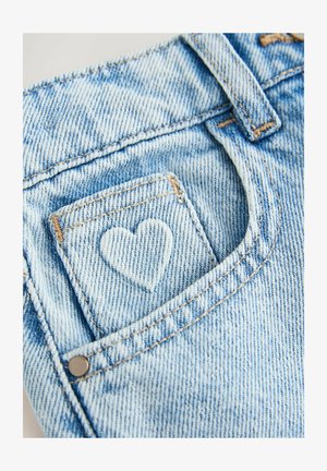 Hele sinised teksapüksid tagataskul südamekujulise õmblustega detailiga. Omavad kontrastset õmblust ja nähtavat metallist nööpi.