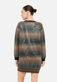 Abito in maglia con una sfumatura di marrone, nero e una texture di paillettes argentate. Presenta maniche lunghe e un orlo a costine.