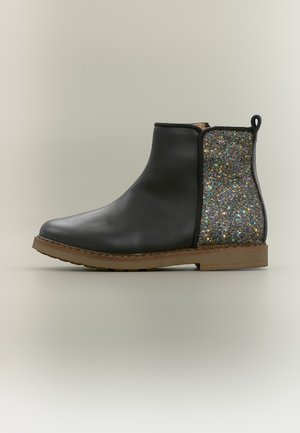 Bottine en cuir noir avec semelle marron et panneau en tissu multicolore pailleté sur le côté du talon sur un fond neutre.