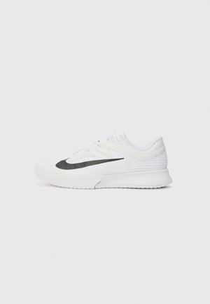 Chaussure de sport blanche avec le logo Nike noir, semelle texturée et design à lacets, vue de profil sur un fond clair uni.