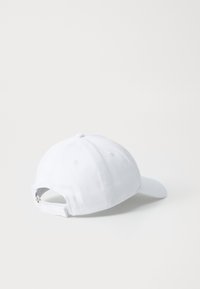 White cotton baseball cap with a rounded crown, curved brim, and adjustable strap in the back. Features ventilation holes for breathability.