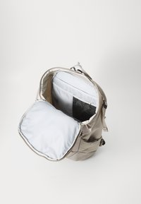 Beige fabric backpack with a spacious interior, light gray lining, and a mesh pocket. Features a padded compartment and dual zippers.