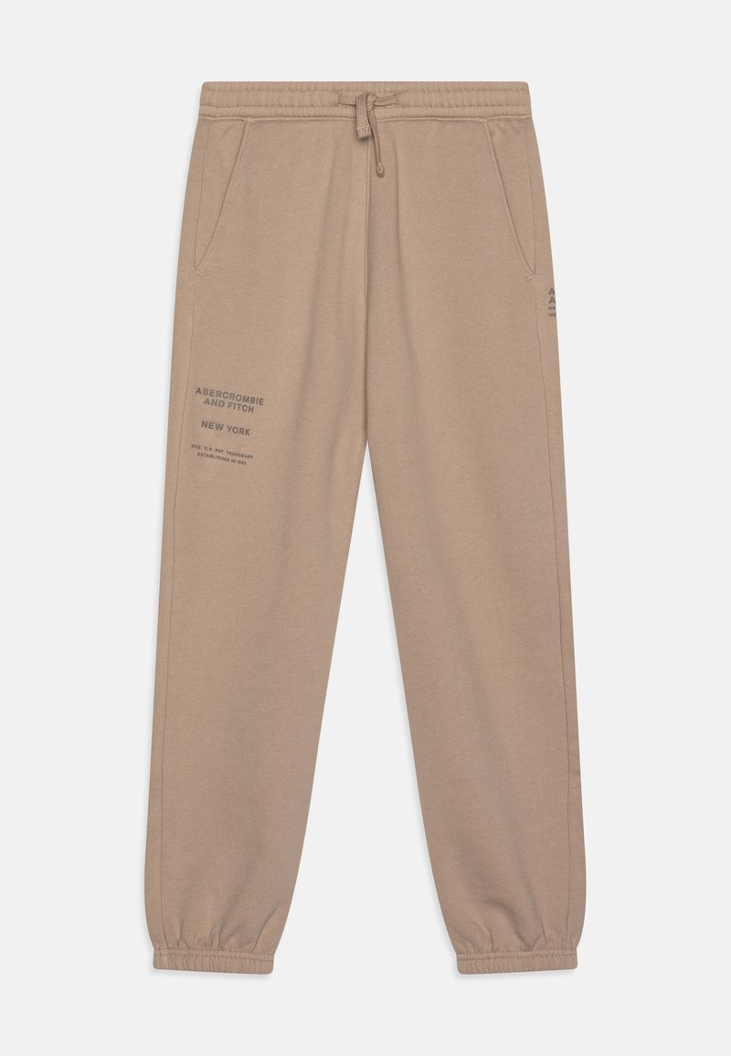 Calças jogger beges feitas de um tecido de algodão misto. Apresentam punhos elásticos, bolsos laterais e uma marca impressa na coxa esquerda.