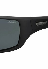 Occhiali da sole in plastica nera con lenti grigie, dotati di un logo Polaroid sulla lente e di un accento metallico sul lato della montatura.