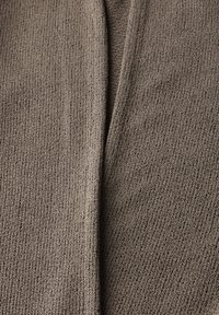 Nahaufnahme eines taupefarbenen Strickstoffs mit sichtbarer, vertikaler Rippstruktur und einer zentralen Naht.