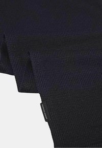 Écharpe texturée bleu marine foncé avec un motif côtelé. Étiquette de logo distincte visible à une extrémité. Le matériau semble doux et tissé.