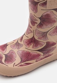 Botte de pluie en caoutchouc beige arborant un motif de feuilles de ginkgo roses, avec une semelle texturée et une finition lisse. Accentuée de subtils contours sombres.