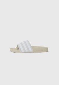 Lys grå slidesandal med en tekstureret rem, der har tre hvide lodrette striber. Blød sål, minimalistisk design og brandlogo på siden.