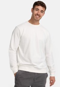 Sudadera blanca de manga larga y cuello redondo, confeccionada en tela suave. Presenta puños y dobladillo de canalé, diseño minimalista sin patrones.