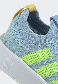 Light blue knit sneaker featuring lime green stripes, white rubber sole, and a yellow pull tab at the heel for easy wear.