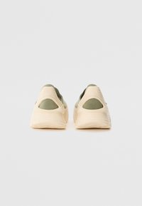 Green knit sneakers with a beige textured sole and accents. Slip-on design with a low profile and open heel for breathability.