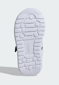 Sole obuvi Adidas v texturované bílé gumě s kruhovými úchyty a vertikálními drážkami, s vyraženým logem uprostřed.