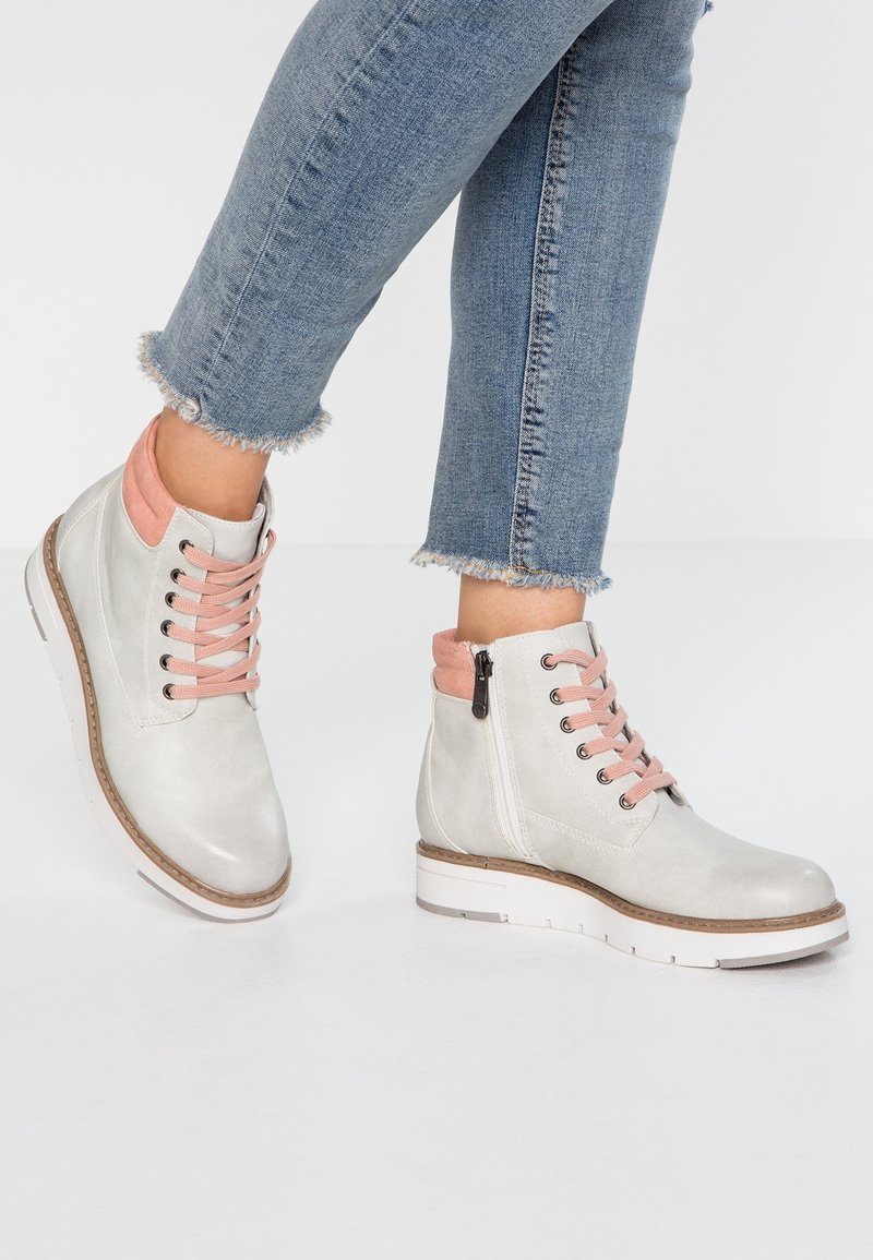 Bottines ankle grises claires en cuir avec des accents roses, présentant un design à lacets, une fermeture éclair latérale et une semelle blanche rembourrée.