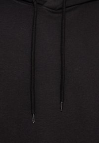 Felpa nera con cappuccio caratterizzata da un tessuto testurizzato, due lacci al collo, maniche lunghe e un design a vestibilità rilassata.