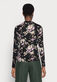 Camicia a maniche lunghe in tessuto nero con un motivo floreale in viola, bianco e verde. Presenta un collo rotondo e una vestibilità aderente.