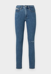 Ξεθωριασμένο μπλε τζιν παντελόνι με στενή γραμμή, με σκισμένη λεπτομέρεια στο δεξί γόνατο και κλασικό σχέδιο με πέντε τσέπες.