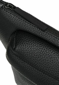 Schwarze Crossbody-Tasche aus strukturiertem Leder mit Reißverschluss und dezentem Logo-Akzent. Abgerundete Kanten und eine glatte Oberfläche prägen das Design.