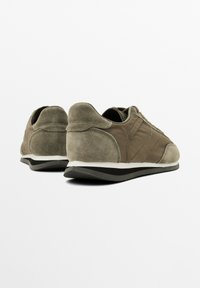 Sneaker in suede e tessuto marrone con profilo basso, dettagli testurizzati e suola intermedia bianca. Presenta una suola in gomma nera durevole.