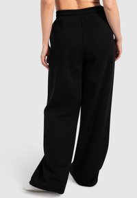 Schwarze, weit geschnittene Sweatpants mit einem strukturierten elastischen Bund, seitlichen Taschen und einem glatten Baumwollmix. 