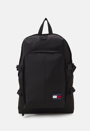 Mochila negra con bolsillo delantero con cremallera y parche con el logo de Tommy Jeans en la esquina inferior derecha, con correas laterales con hebillas y asa superior.