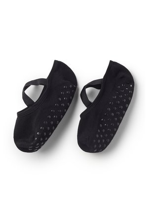 Schwarze Ballettsocken mit rutschfesten Gummipunkten an den Sohlen und elastischen Riemen, vor weißem Hintergrund abgebildet.