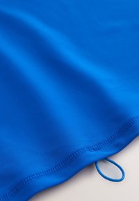 Klart blåt stof med en glat tekstur. Har en syet kant med en løkke i den ene ende til ophængning. Velegnet til forskellige formål.