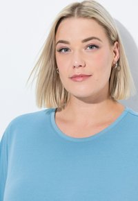 T-shirt a maniche corte, con collo rotondo, in cotone misto azzurro chiaro, caratterizzato da una texture liscia e una vestibilità rilassata. Dettagli minimi, nessuna grafica.
