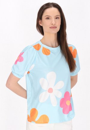 Lys blå kortærmet top med store, farverige blomster mønstre i pink, orange og hvid. Blødt materiale med en afslappet pasform.