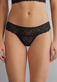 Schwarze Spitzenunterhosen mit intricaten Blumenmustern, gewellten Kanten und einer weichen, halbtransparenten Textur.