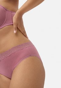 Ropa interior de algodón ribeteado en rosa polvo con un borde de encaje en la cintura, que presenta una textura suave y un diseño sin costuras.