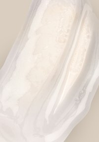 Superficie in onice bianco con texture liscia e lucida, caratterizzata da sottili venature grigie e leggere variazioni di colore, creando un effetto marmorizzato.