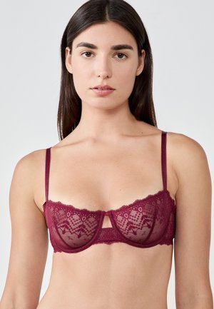 Sujetador de encaje burdeos con aros, tirantes ajustables y patrones geométricos. Diseño con centro abierto, bordes festoneados y tela translúcida.