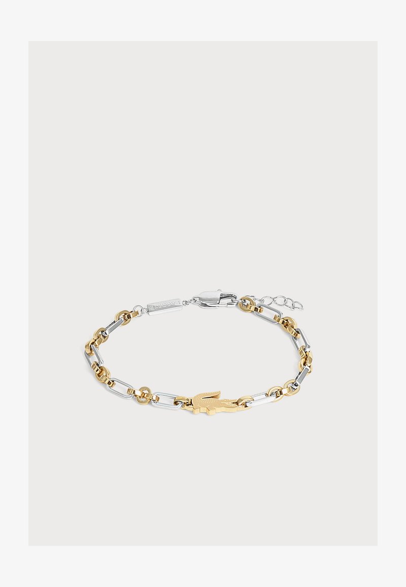 Bracelet chaîne en métal bicolore avec un emblème crocodile doré et une fermeture à mousqueton argentée.