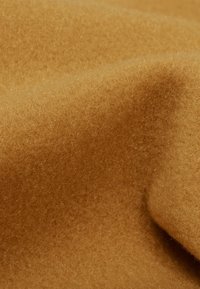 Tessuto morbido e testurizzato in una calda tonalità marrone dorato, con un aspetto denso e soffice, caratterizzato da sottili variazioni di tonalità.