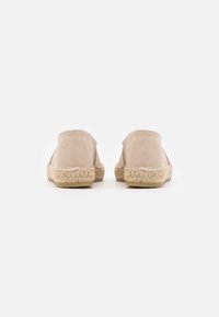 Scarpe slip-on in suede blush con suola intrecciata in juta e dettagli cuciti; design con retro arrotondato, texture liscia, stile minimalista.