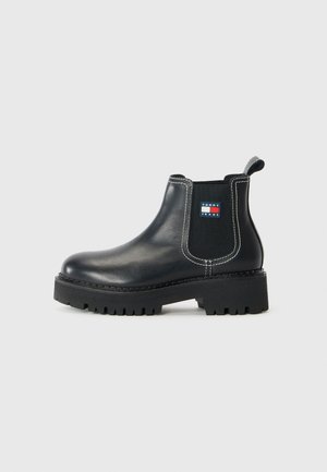 Sort læderankelstøvle med chunky sål, elastisk sidepanel, trækflig, hvide syninger og Tommy Jeans-logo på ydersiden.