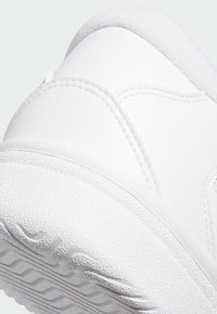 Vit sneaker med en texturerad yta, rund tå och diskreta sömnadsdetaljer. Sulan har ett vågigt mönster för bättre grepp.