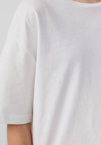 Witte katoenen t-shirt met een ronde hals, korte mouwen en een losse pasvorm. De stof lijkt zacht en lichtjes gestructureerd.