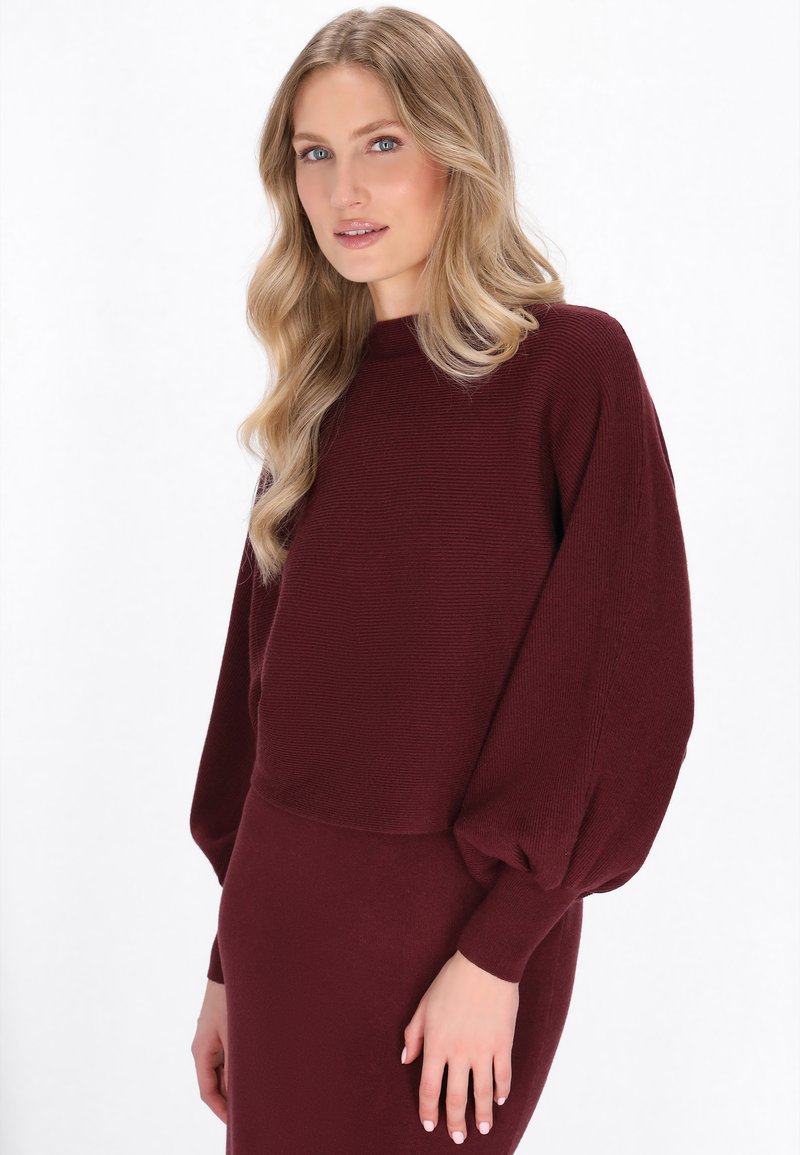 Burgunderfarbener Rippstrickpullover mit Ballonärmeln, strukturiertem Stoff, rundem Kragen und taillierter Passform, kombiniert mit einem passenden Rock.