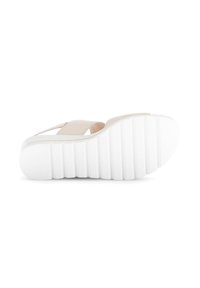 Beige slip-on sandaal met een gestructureerde bovenkant en een witte, gegroefde rubberen zool. Het ontwerp heeft gekruiste banden voor ondersteuning.