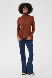Rozsda színű garbó pulóver puha, texturált kötésből, sötétkék, bővülő szabású farmerral párosítva. A ruhadarab hosszú ujjú és laza szabású.