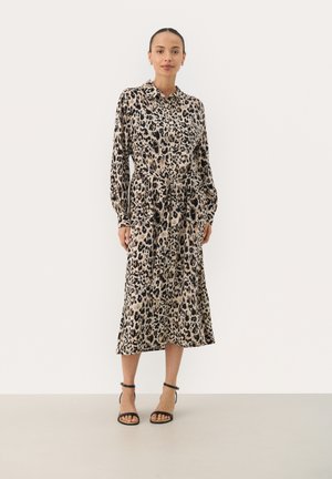 Robe chemise à imprimé léopard avec manches longues, taille ceinturée et longueur midi. Le tissu semble lisse, avec une palette de couleurs beige clair et noir.