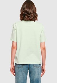 Light green cotton t-shirt with short sleeves, a relaxed fit, and a rounded neckline, paired with blue denim jeans.