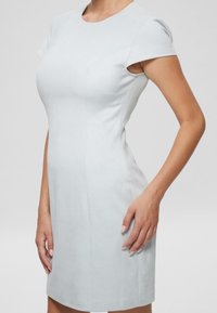 Vaaleansininen, vartalonmyötäinen mekko, jossa on lyhyet hihat, pyöreä pääntie ja tarkasti määritellyt saumat. Mekko on valmistettu sileästä, hieman teksturoidusta kankaasta.