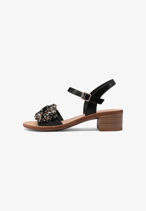 Sandali con tacco in pelle nera, caratterizzati da una larga fascia per le dita con una decorazione in gioiello e una cinturino alla caviglia con fibbia. Tacco a blocco con effetto legno.