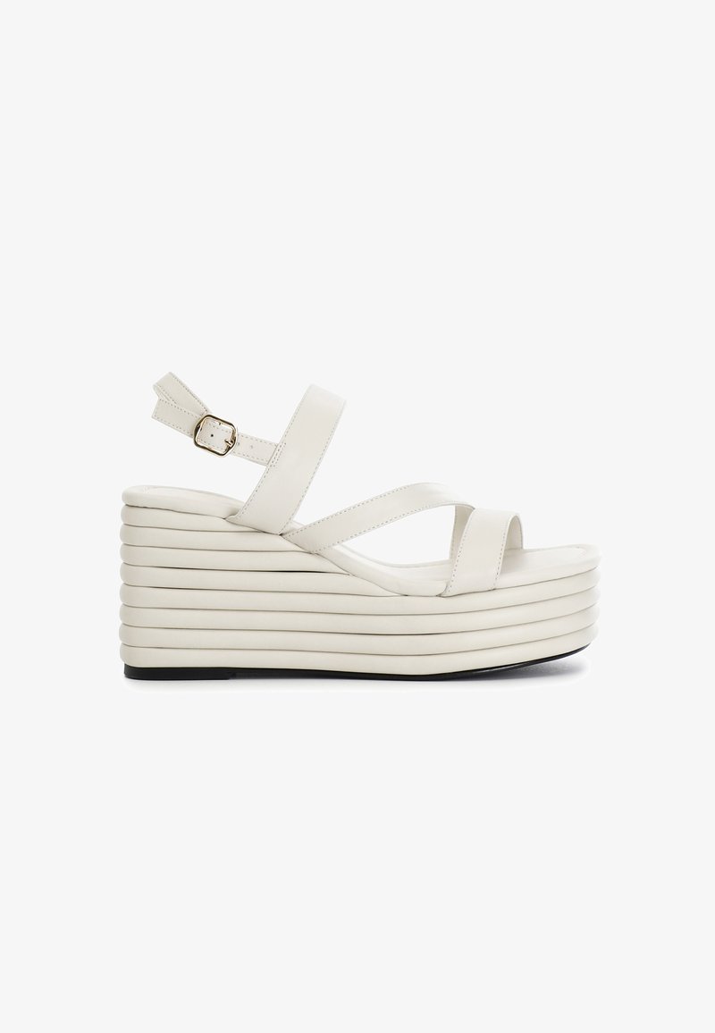 Sandali wedge bianchi con una suola testurizzata a strati. Presentano una cinghia alla caviglia regolabile e fasce frontali incrociate per una vestibilità sicura.